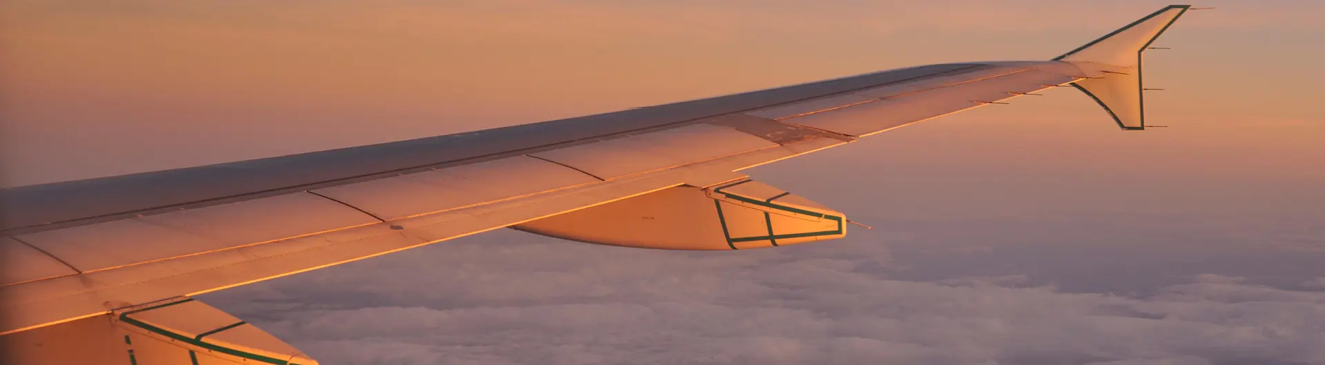 Plane wing in sky above clouds